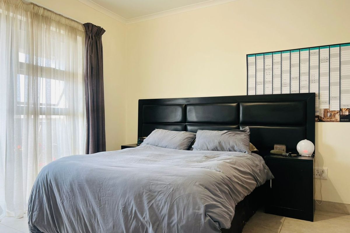 A well-maintained bedroom featuring tiled flooring and a large sliding glass door that provides natural light.
