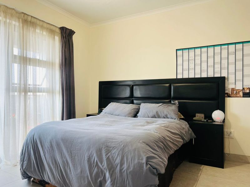 A well-maintained bedroom featuring tiled flooring and a large sliding glass door that provides natural light.