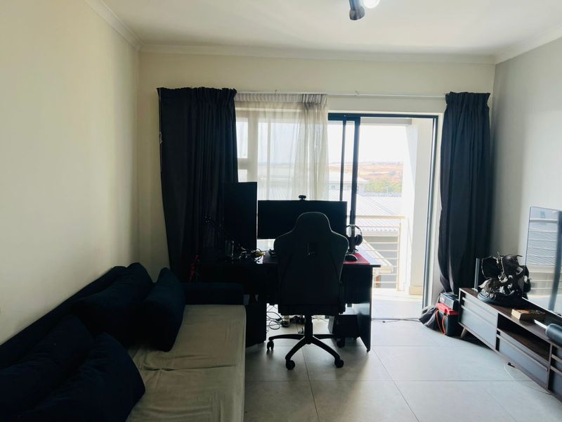 A living room area featuring tiled flooring and a sliding glass door providing access to an outdoor balcony space.