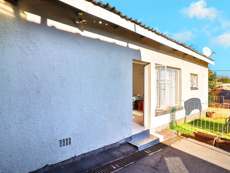 Rear exterior view of the property featuring a plastered facade, tiled roof, and security bars on the windows.