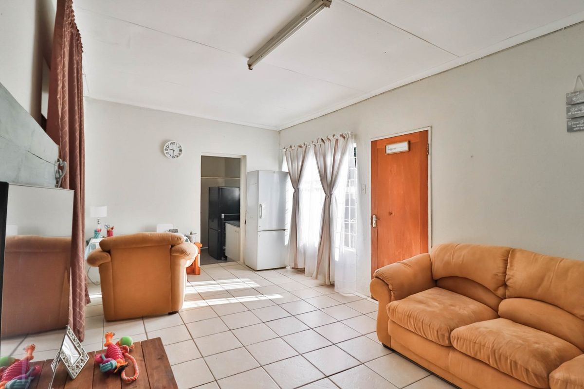 A living area featuring tiled flooring and direct access to an adjacent utility space, offering a functional layout with neutral wall finishes.