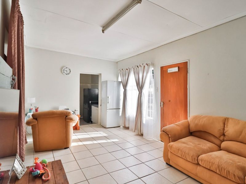 A living area featuring tiled flooring and direct access to an adjacent utility space, offering a functional layout with neutral wall finishes.