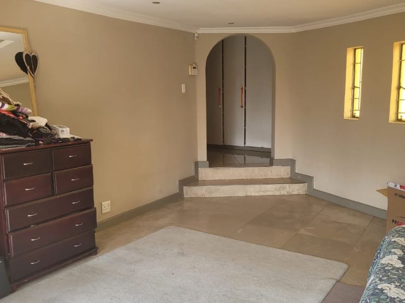 Spacious bedroom featuring a unique arched entryway with tiled steps leading to built-in storage and a recessed ceiling design.
