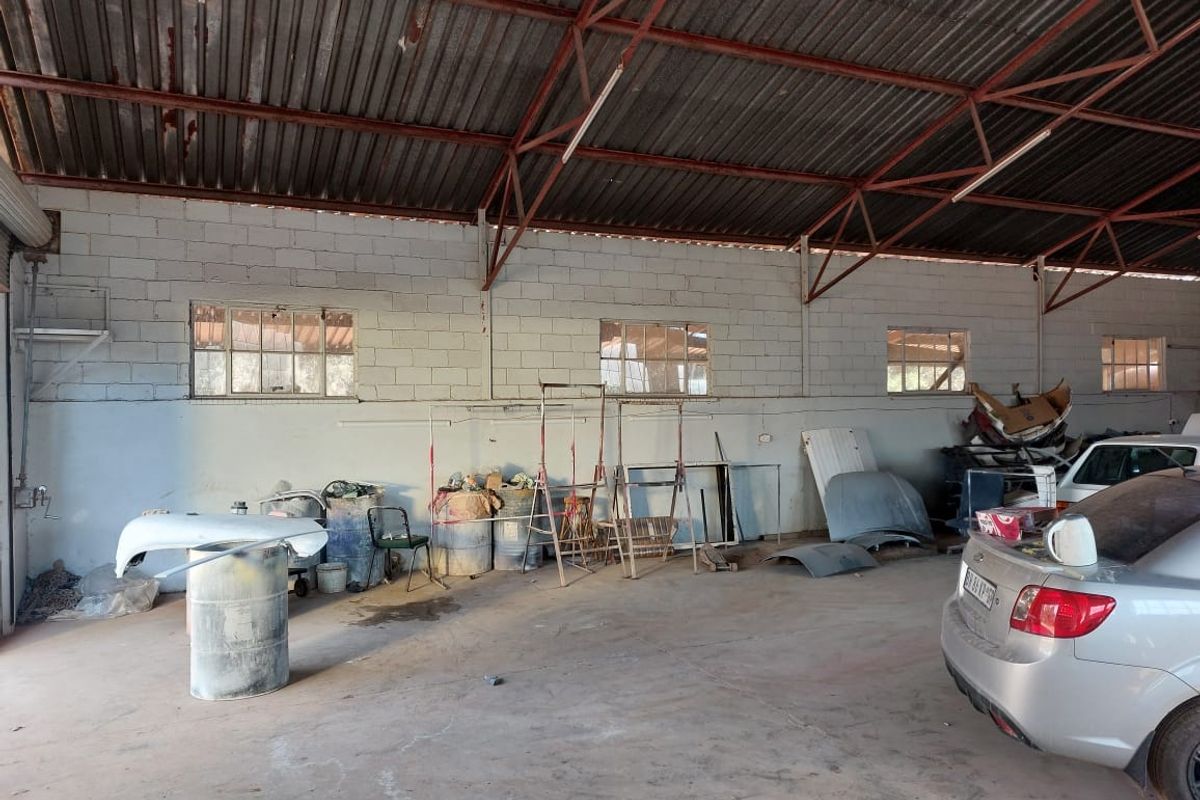 Spacious industrial utility workshop featuring exposed steel roof trusses, corrugated metal roofing, and durable concrete flooring, suitable for various commercial or storage applications.