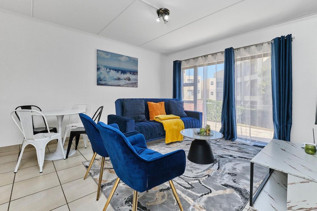 A bright living room featuring tiled flooring and a large sliding glass door that provides natural light and access to the exterior.