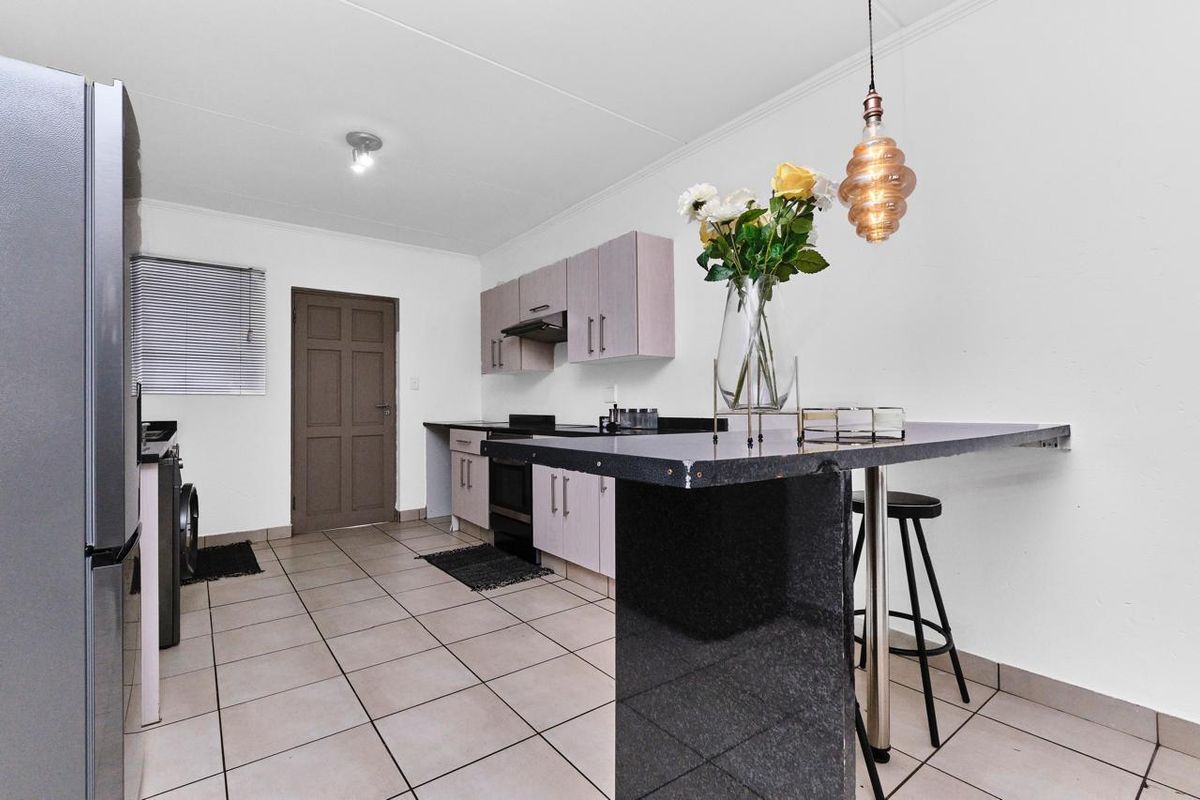 Functional kitchen featuring built-in cabinetry, granite countertops, a breakfast bar, and ceramic floor tiles, providing a practical workspace.