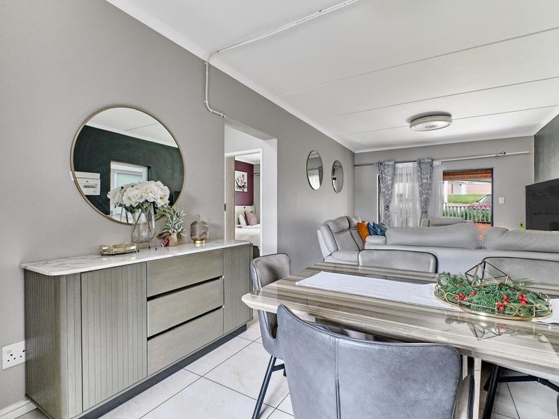 Open-plan living and dining area featuring neutral wall tones, tiled flooring, and direct access to the exterior patio.