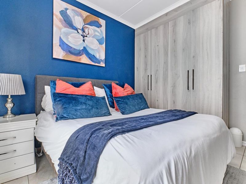 A well-maintained bedroom featuring built-in cupboards with a modern wood-grain finish and tiled flooring.