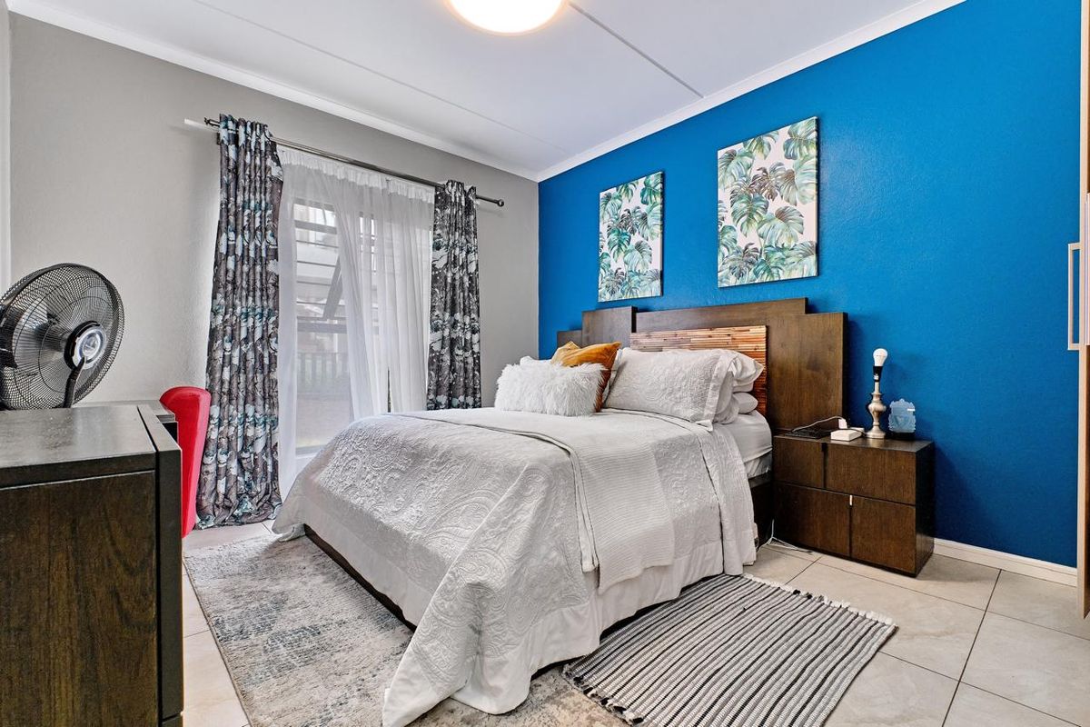 A well-maintained bedroom featuring tiled flooring, a built-in headboard, and a sliding glass door providing access to the exterior.