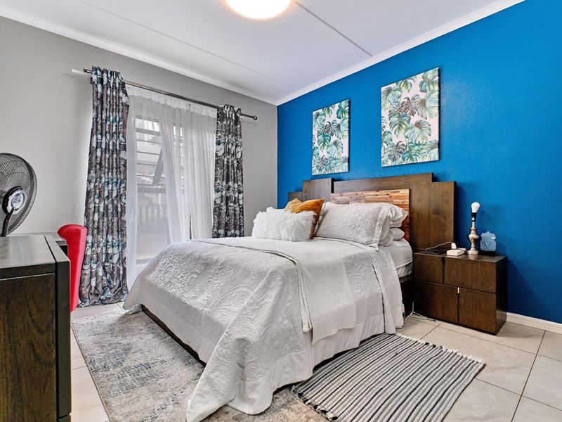 A well-maintained bedroom featuring tiled flooring, a built-in headboard, and a sliding glass door providing access to the exterior.