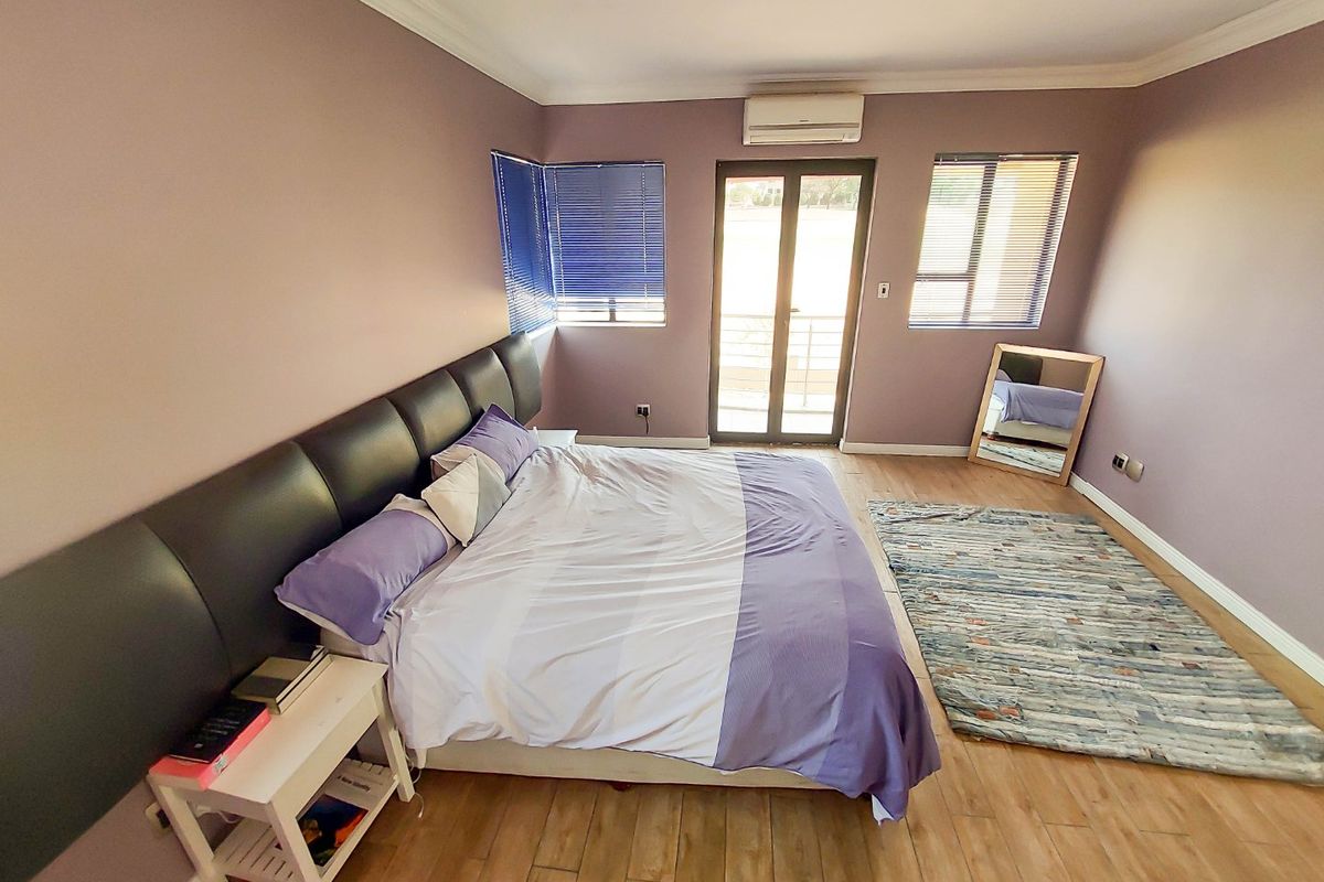 Spacious bedroom featuring laminate flooring, an integrated air conditioning unit, and direct access to an outdoor area through sliding glass doors.