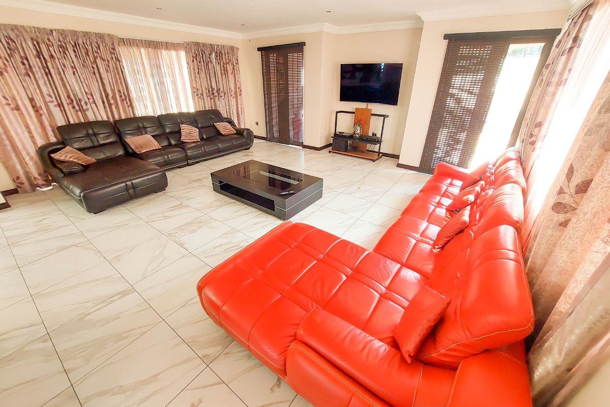 Spacious living room featuring large format marble-look floor tiles, recessed ceiling lighting, and multiple access points to outdoor areas via sliding doors.