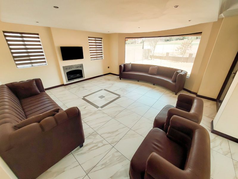 Spacious living room featuring large format tiled flooring, a built-in fireplace, and a expansive picture window offering natural light and views.