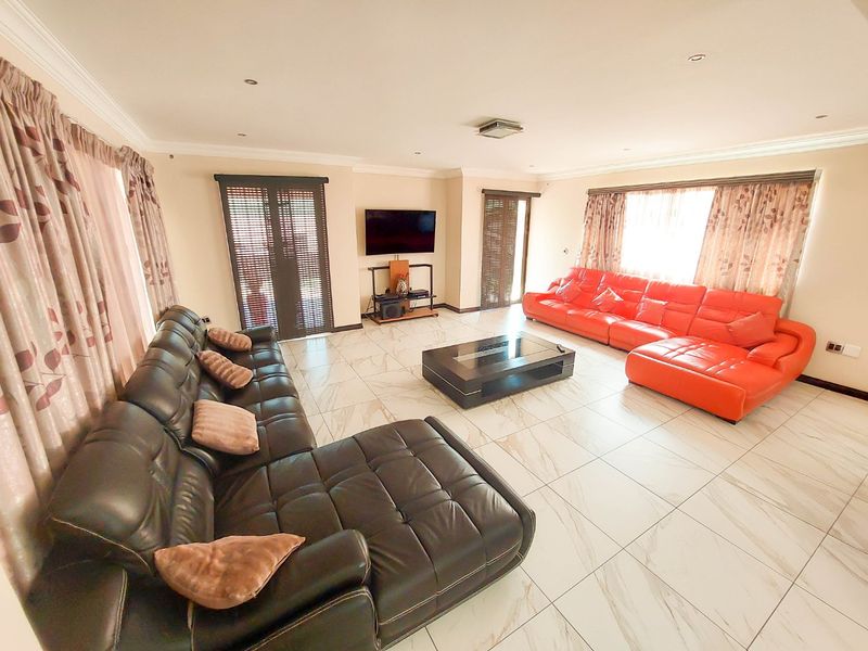 Spacious living room featuring large format marble-look floor tiles, recessed downlighting, decorative cornicing, and sliding door access to the exterior.