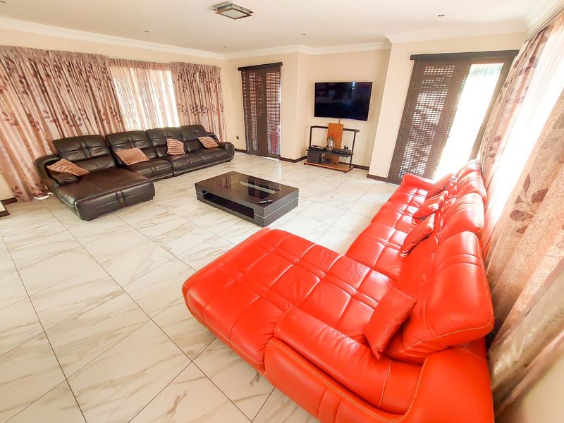 Spacious living room featuring large-format marble-look floor tiles, recessed ceiling lighting, and multiple sliding glass doors providing access to the exterior.