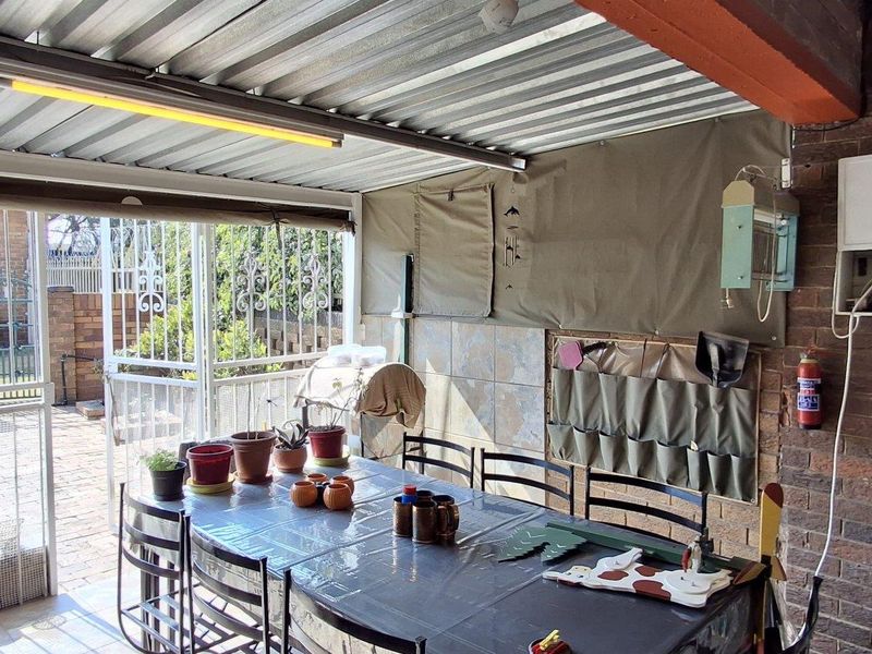 Covered outdoor patio area featuring a corrugated metal roof, brick walling, and secure gated access to the garden.