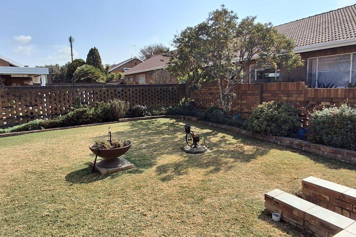 A private rear garden featuring a lawn, established trees, and a brick boundary wall, providing a secure outdoor space.
