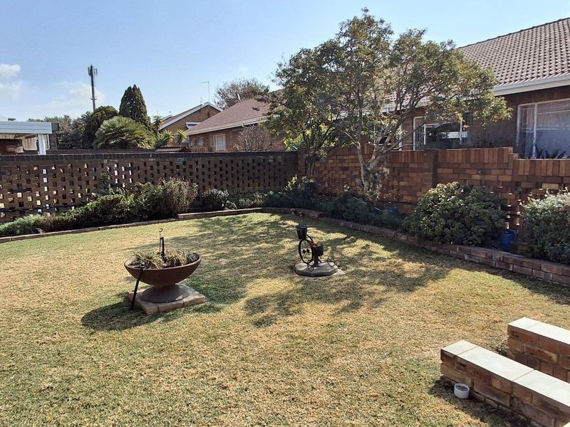 A private rear garden featuring a lawn, established trees, and a brick boundary wall, providing a secure outdoor space.