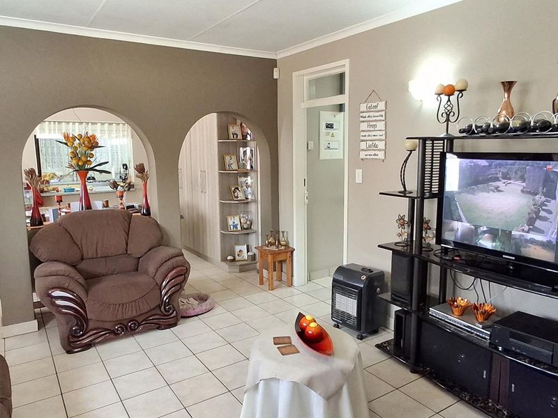 A living room featuring tiled flooring, arched architectural dividers, and built-in shelving, providing a functional and connected living space.