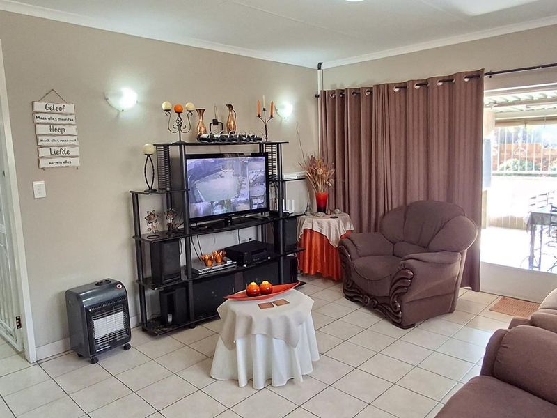 A comfortable living room featuring tiled flooring, neutral wall tones, and a sliding glass door providing access to the outdoor patio area.