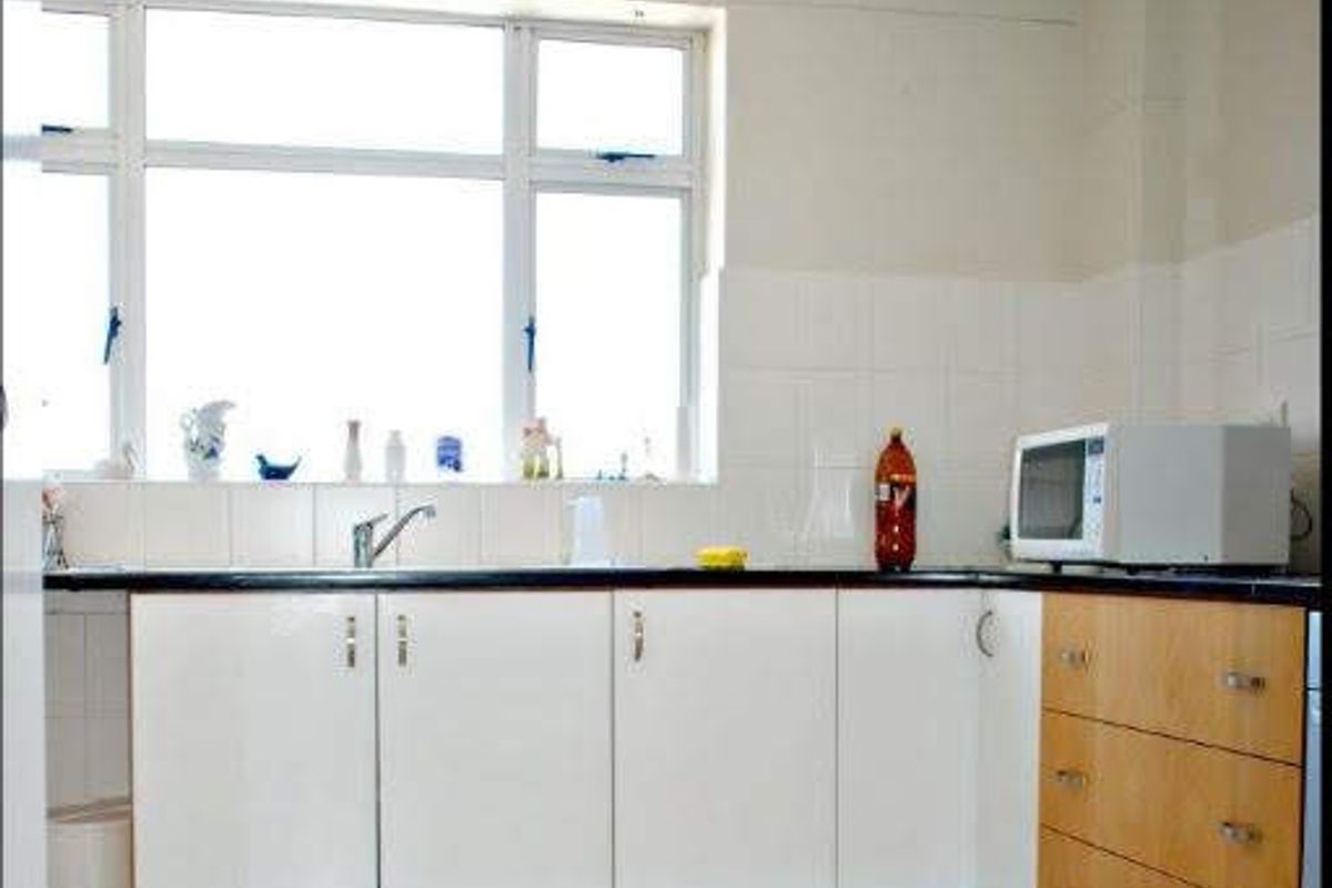 A functional kitchen featuring white and wood-tone cabinetry, tiled backsplash, and tiled flooring, offering a clean and practical workspace.