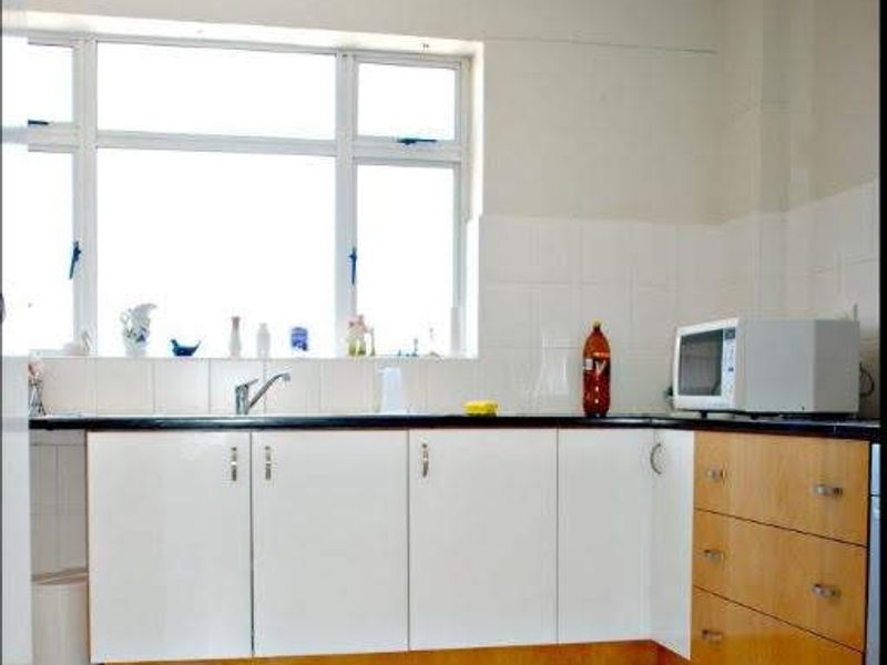 A functional kitchen featuring white and wood-tone cabinetry, tiled backsplash, and tiled flooring, offering a clean and practical workspace.