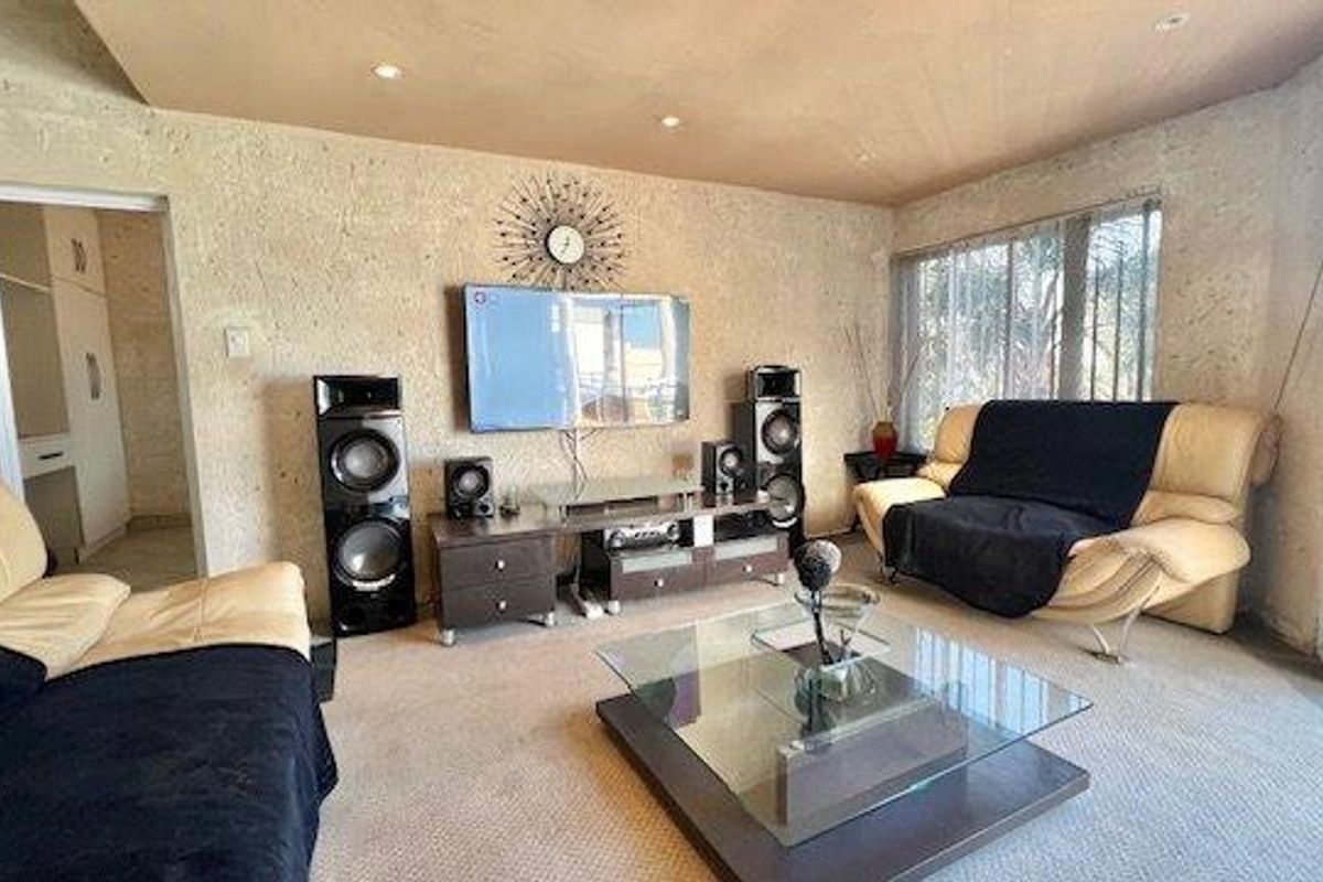 A living room featuring textured walls, recessed downlighting, and access to an outdoor area through a sliding glass door.