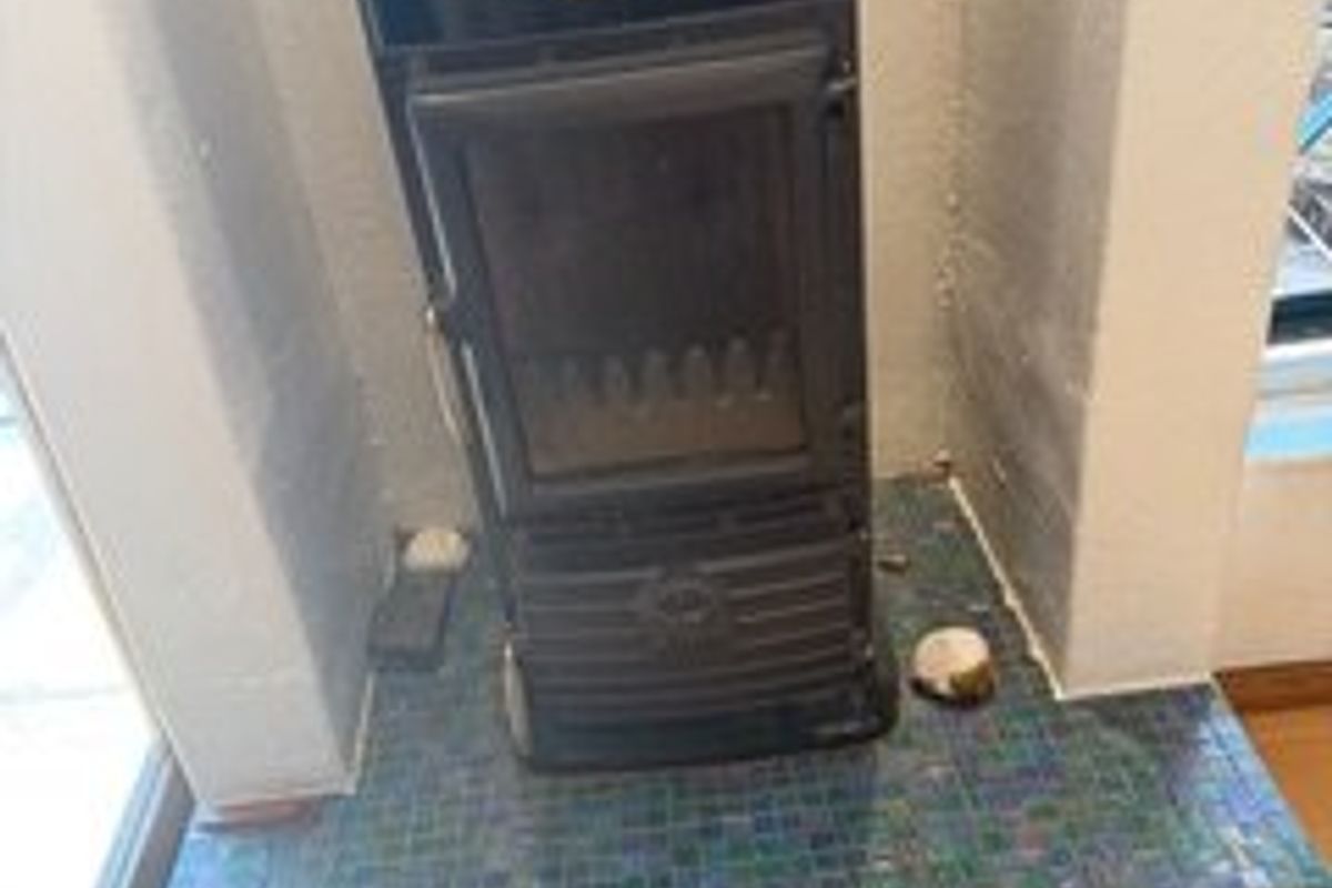 A freestanding fireplace set on a decorative blue mosaic tiled hearth within a living area.
