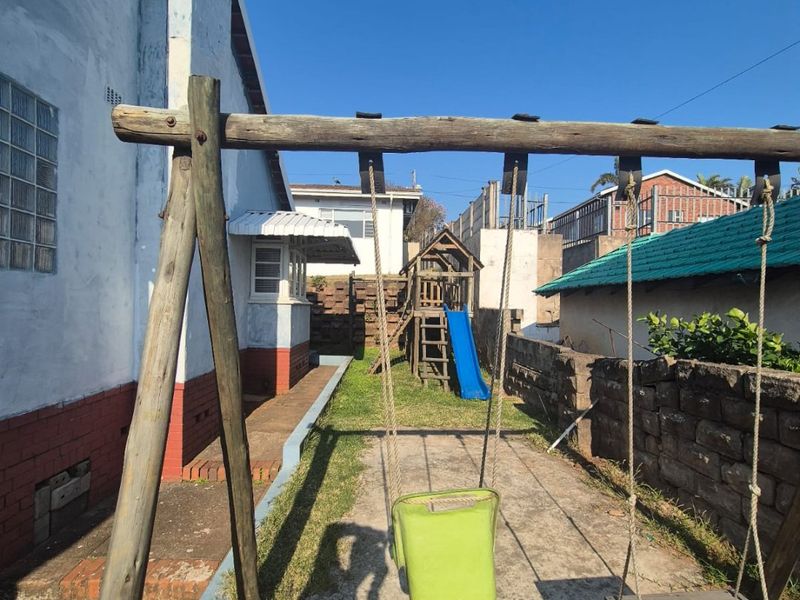 Rear exterior area featuring concrete paving, brick boundary walls, and access to the side of the house with existing structural finishes.