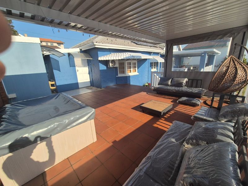 A covered outdoor patio area featuring tiled flooring, an awning, and an air conditioning unit, providing a functional space for outdoor relaxation.