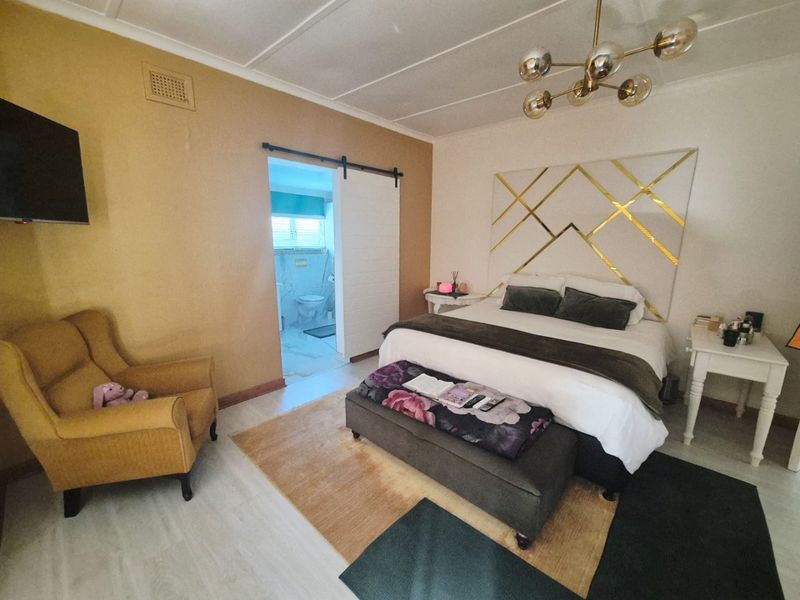 Spacious bedroom featuring a sliding barn door leading to an en-suite bathroom, modern lighting, and a wall-mounted television.