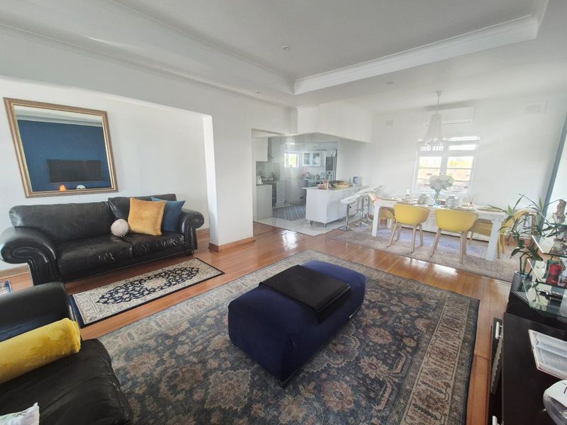 Spacious open-plan living and dining area featuring hardwood flooring, a recessed ceiling, and a seamless transition into the adjoining kitchen space.