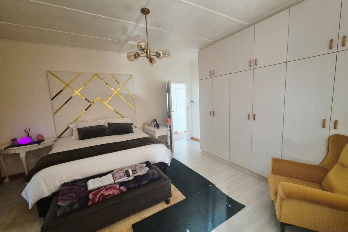 Spacious bedroom featuring extensive built-in cupboards, modern ceiling lighting, and light-toned tiled flooring, offering a clean and functional living space.