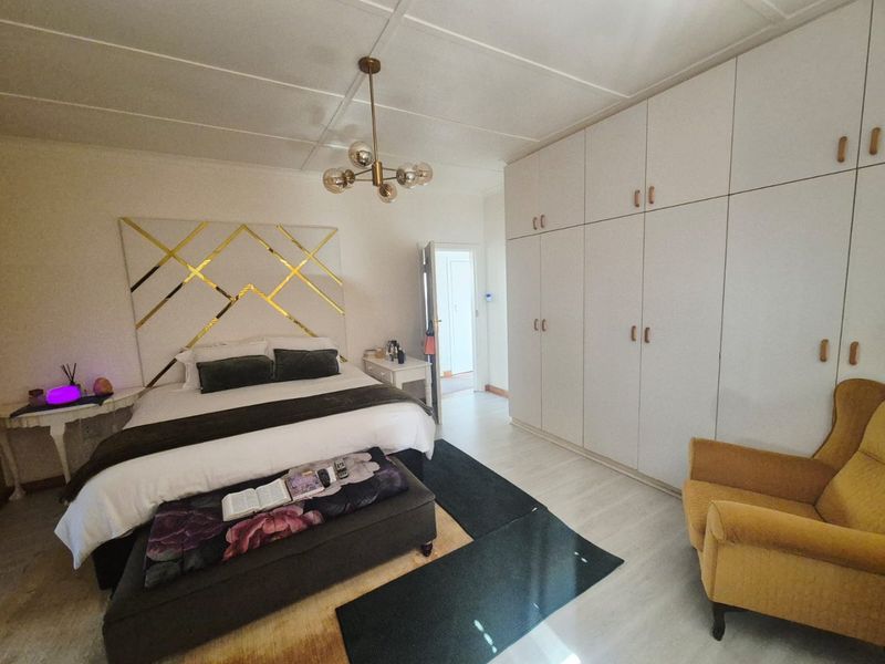 Spacious bedroom featuring extensive built-in cupboards, modern ceiling lighting, and light-toned tiled flooring, offering a clean and functional living space.