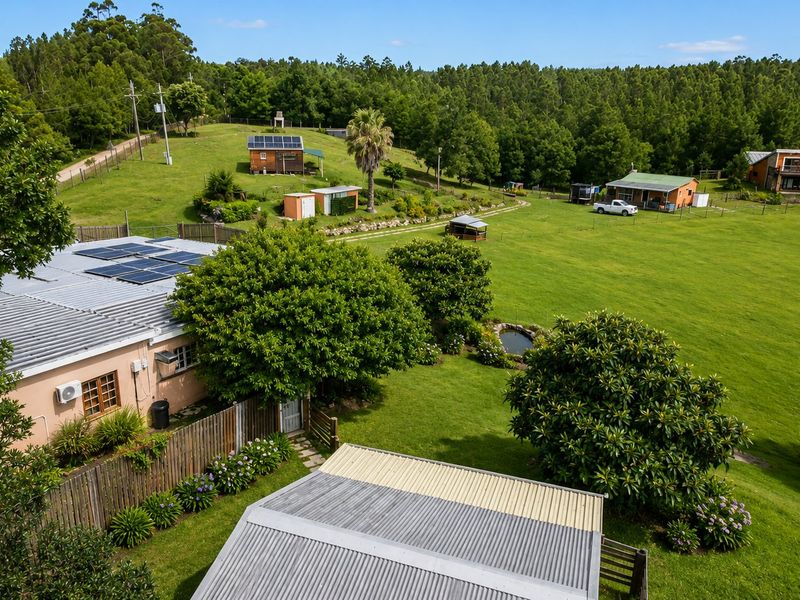 Aerial view of a rural farm property featuring multiple outbuildings, solar panel installations, expansive green lawns, and mature trees.