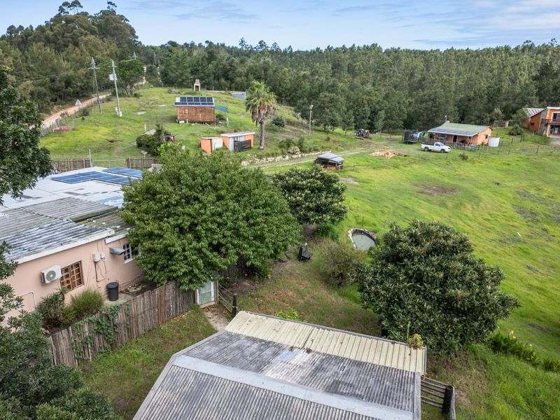 Aerial view of a rural farm property featuring multiple structures, solar panel installations, and expansive green pasture land.