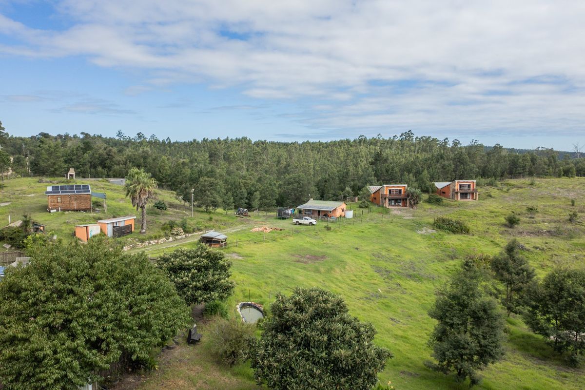 Aerial view of a rural farm property featuring multiple residential buildings, outbuildings, solar installations, and expansive green landscape.
