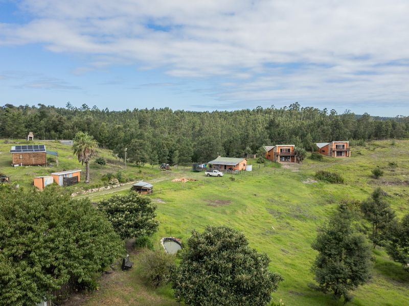 Aerial view of a rural farm property featuring multiple residential buildings, outbuildings, solar installations, and expansive green landscape.