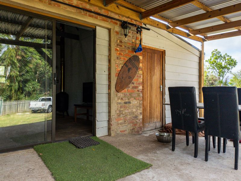 Covered outdoor patio area featuring exposed brickwork, timber rafters, and direct access to the interior through a sliding glass door.