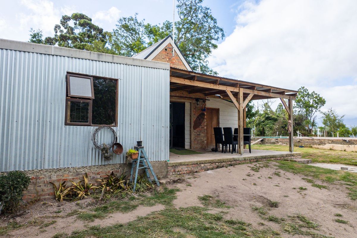 Rear view of the farm property featuring a corrugated metal extension and a covered timber patio area overlooking the garden.