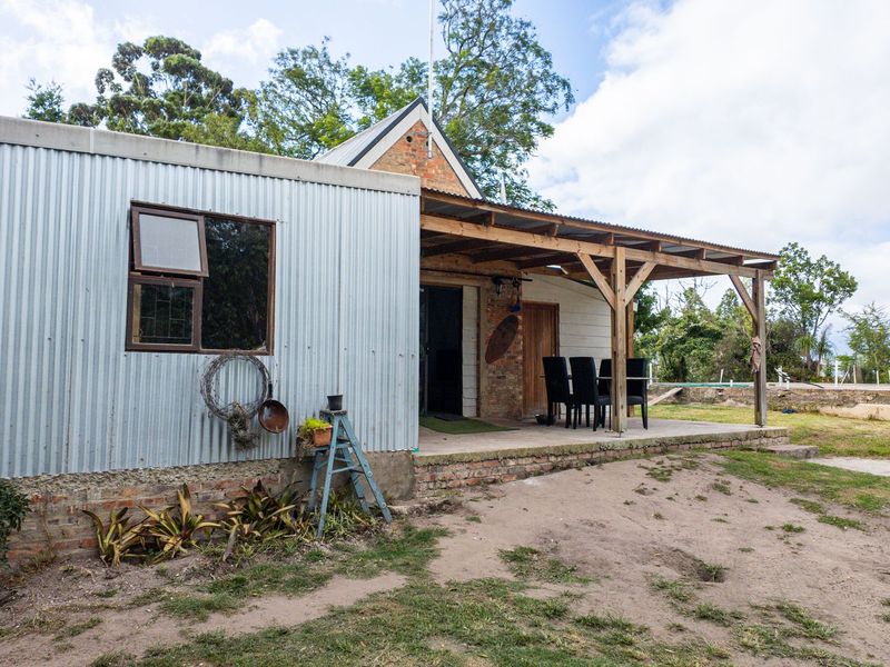 Rear view of the farm property featuring a corrugated metal extension and a covered timber patio area overlooking the garden.