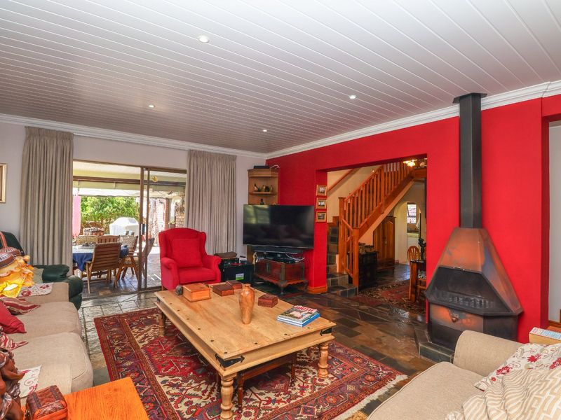 Spacious living room featuring a striking red accent wall, a modern freestanding fireplace, slate flooring, and direct access to an outdoor patio area.