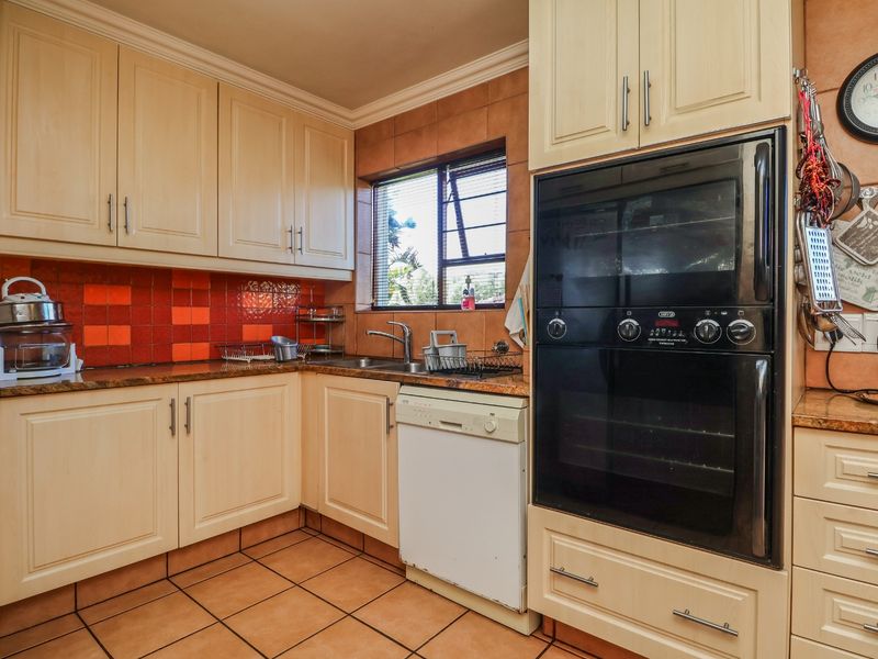 A functional kitchen featuring light-toned cabinetry, a built-in double oven, tiled backsplash, and tiled flooring, offering a classic layout with ample storage.