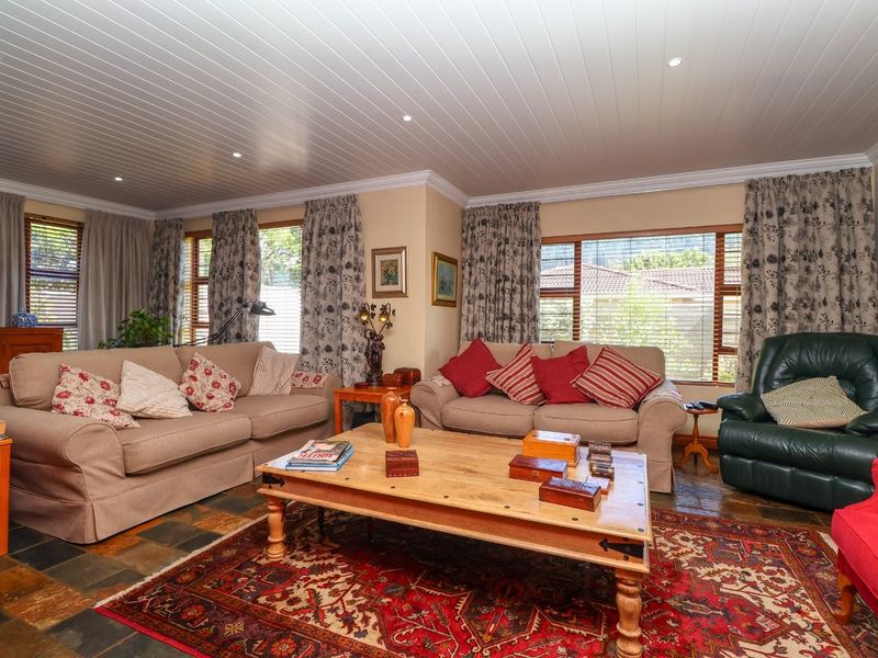 A spacious living room featuring slate tile flooring, a white tongue and groove ceiling with recessed lighting, and large windows providing natural light.