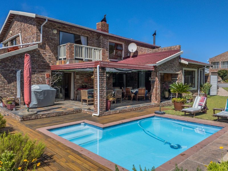 Rear view of a brick house featuring a swimming pool, timber decking, and a covered patio area.