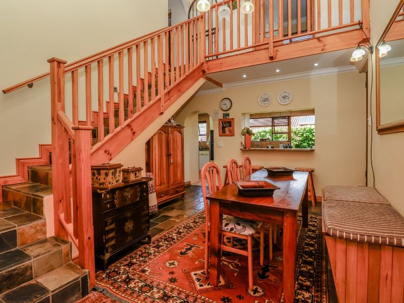 Open plan dining area featuring slate tile flooring, a timber staircase with balustrade, and a convenient pass-through window connecting to the kitchen.