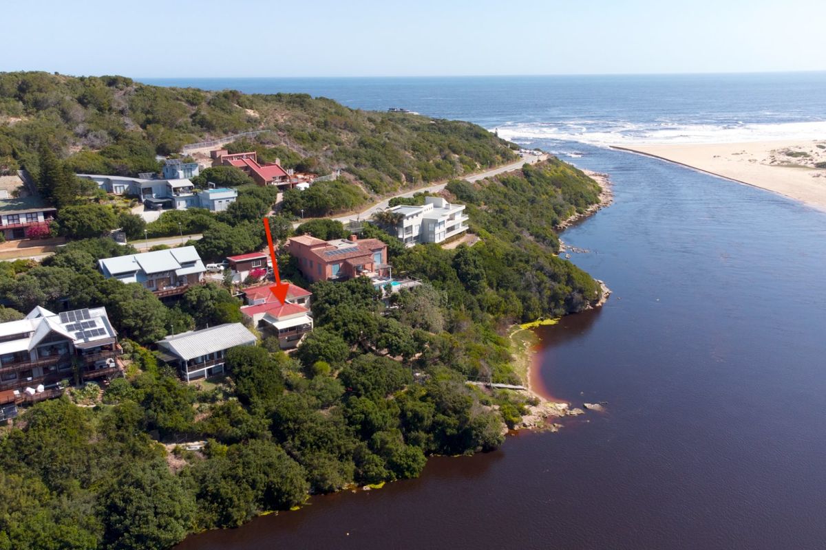 Aerial view of a coastal property situated along a river estuary, showcasing its prime location and proximity to the beach and natural landscape.