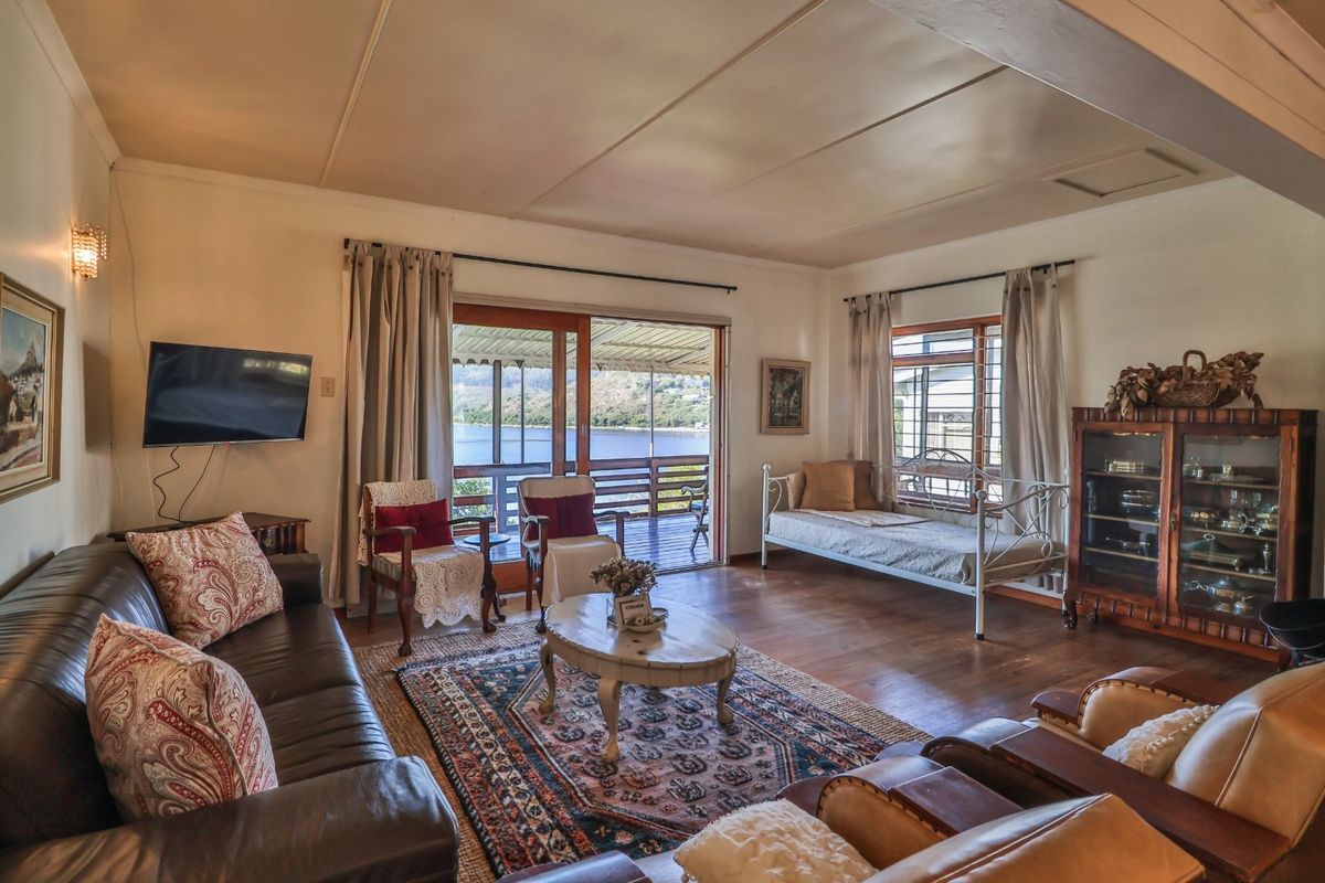 Spacious living room featuring hardwood flooring and large sliding glass doors that provide access to an outdoor deck with scenic water views.