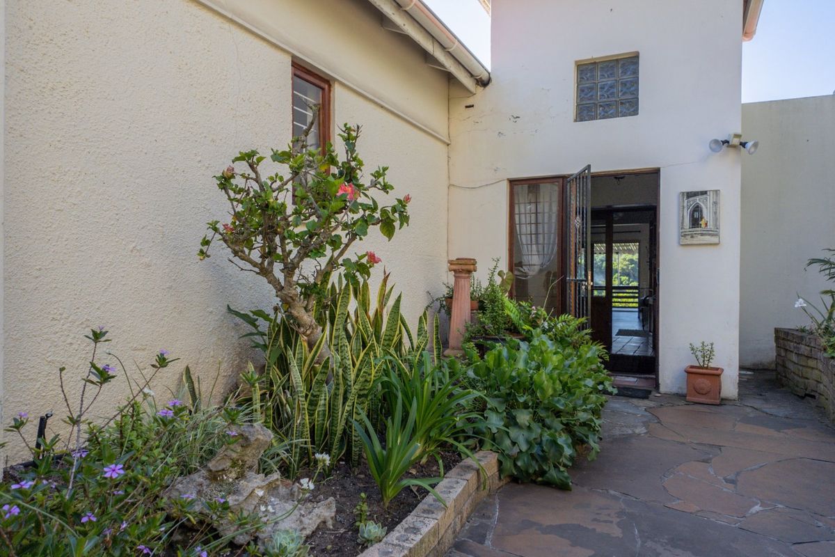 A rear courtyard area featuring stone paving, a raised garden bed, and access to the interior through a security gate and door.