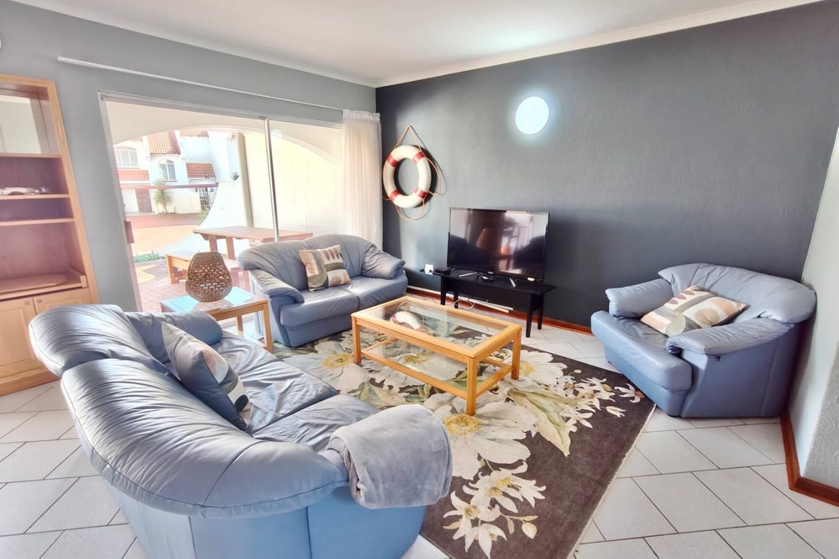 A comfortable living room featuring tiled flooring, a built-in shelving unit, and large sliding glass doors providing access to the outdoor patio area.